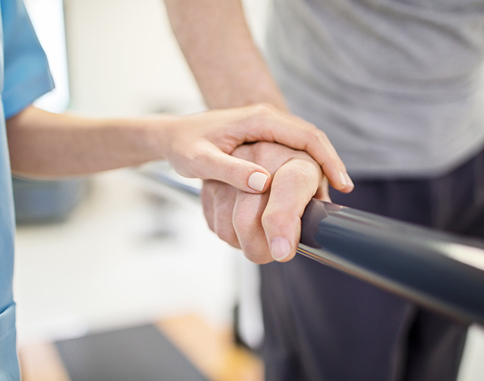 Female nurse touching senior man's hand on railing